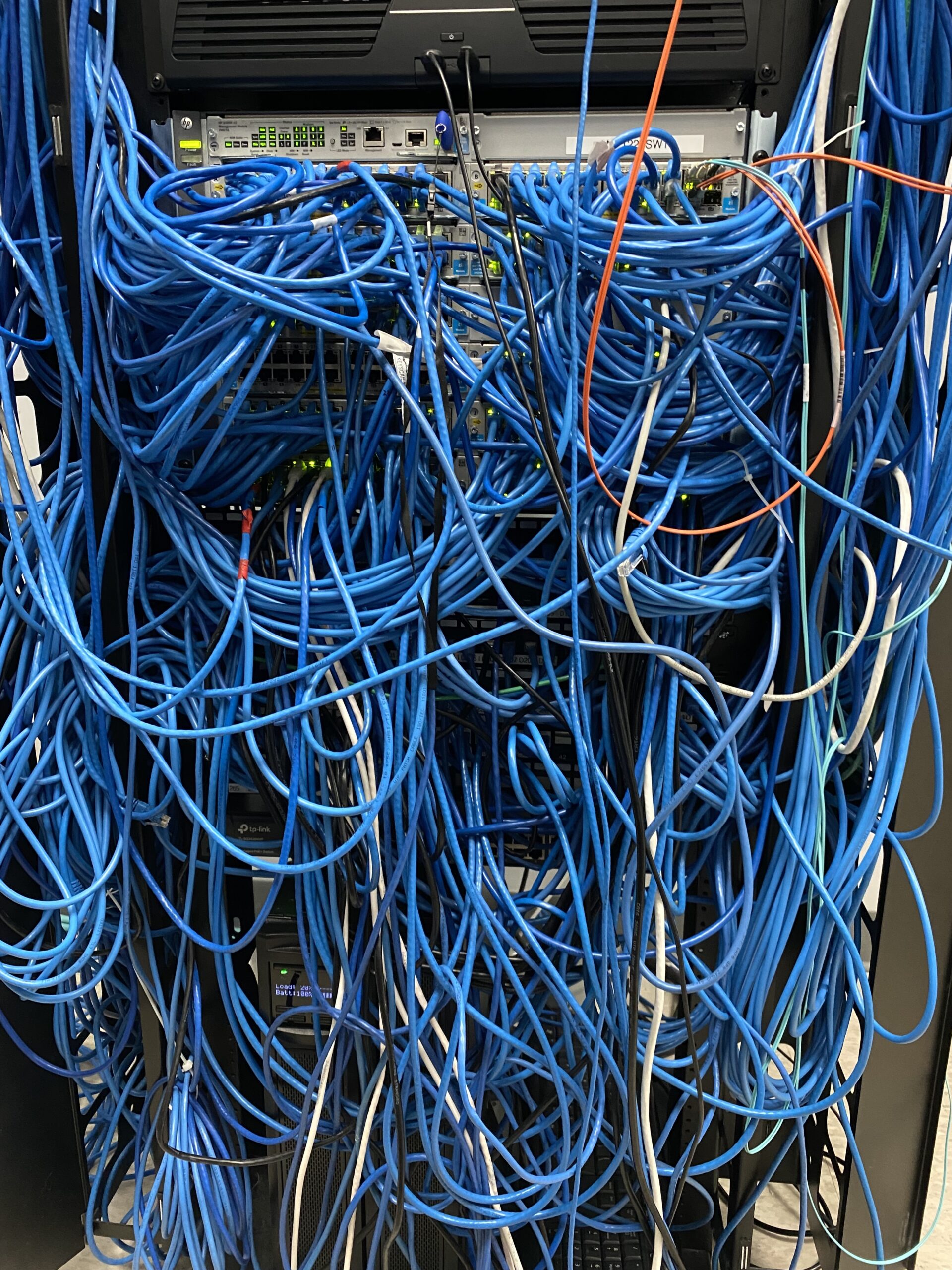 A very messy IT closet in need of structured cabling help.
